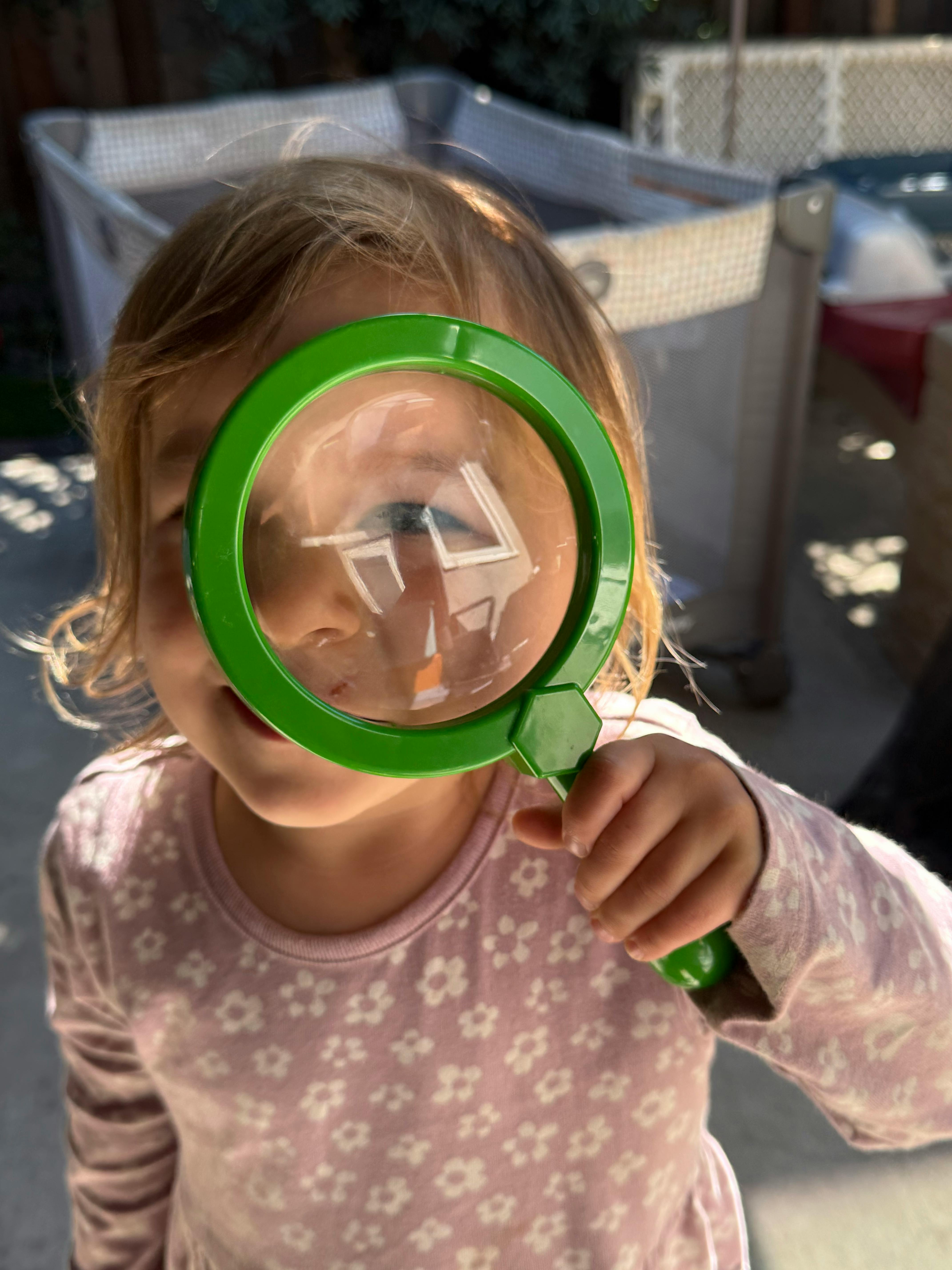 Child looking through a green magnifying glass