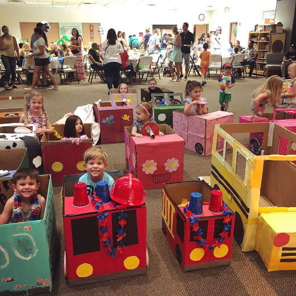 Children playing in decorated cardboard box cars and trucks