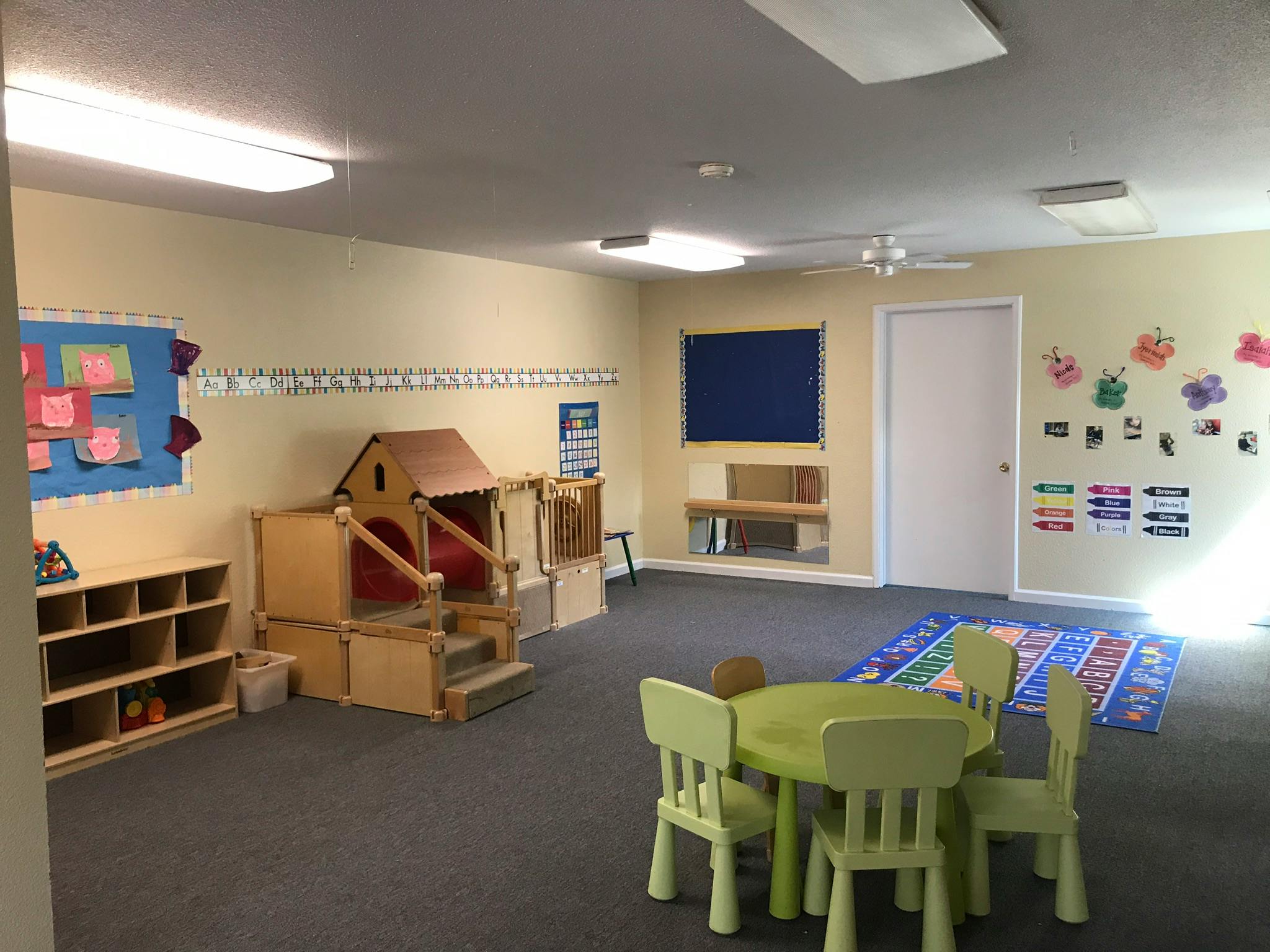 Empty classroom with play structure, cubbies, and small table with chairs