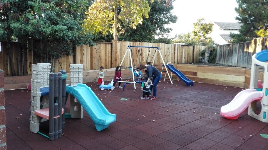 Adult and children on a playground with slides and swings