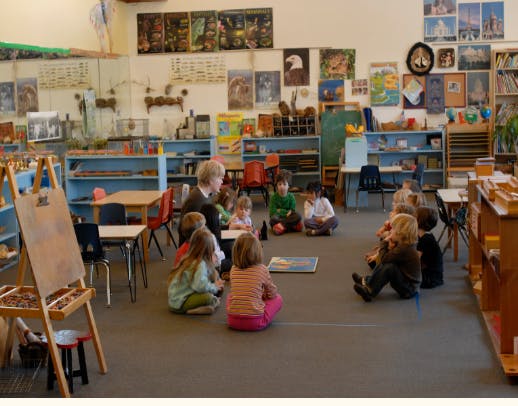 Adult and children sitting on the floor in a classroom