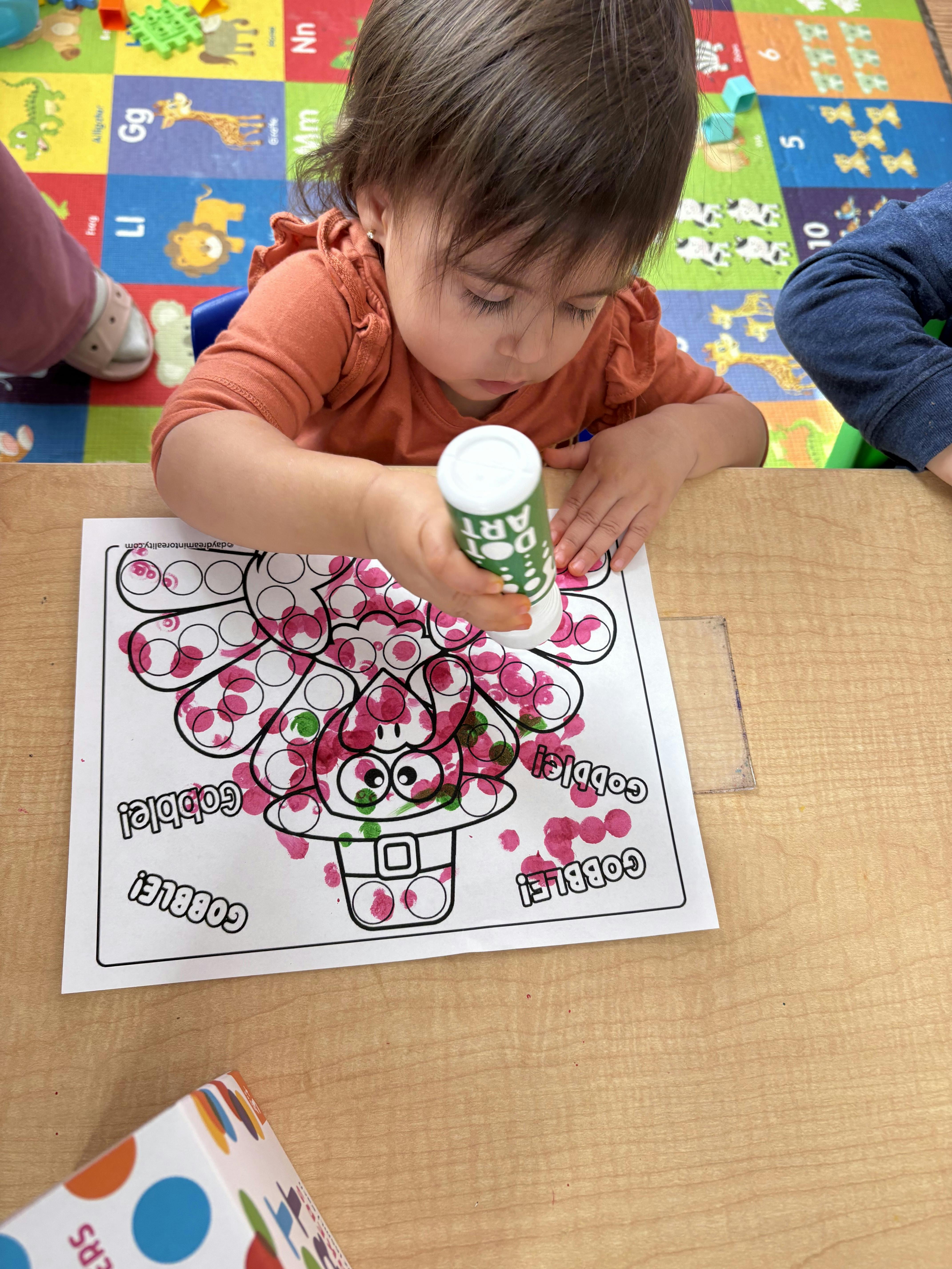 Child using a dot marker on a turkey craft