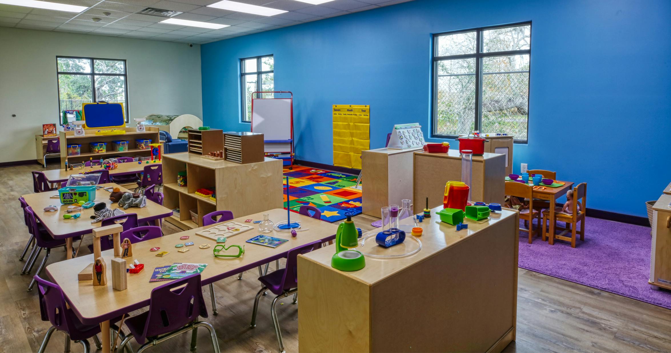 Classroom with child-sized tables and chairs, toys, and learning materials