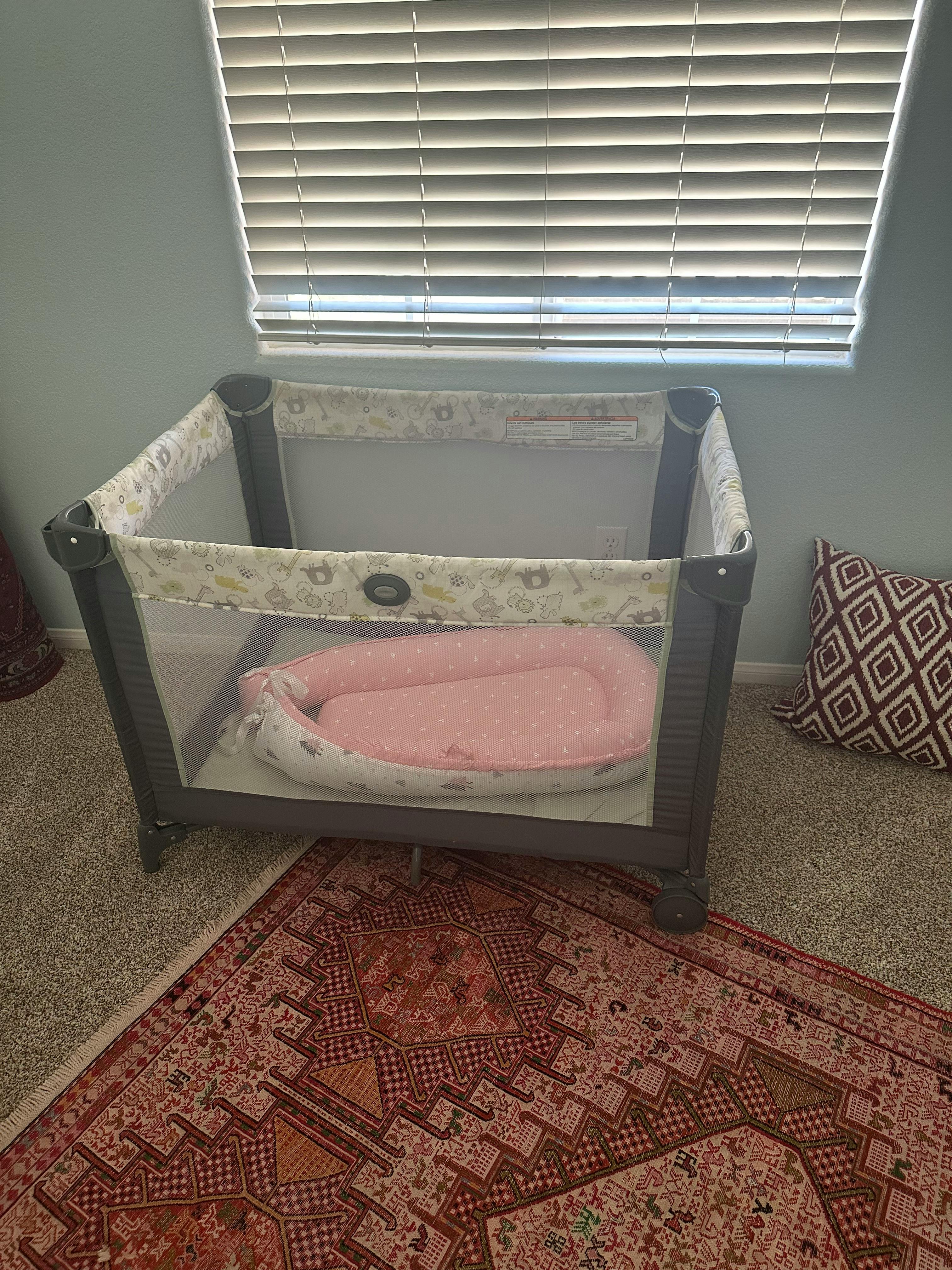 Playard with a pink baby lounger inside