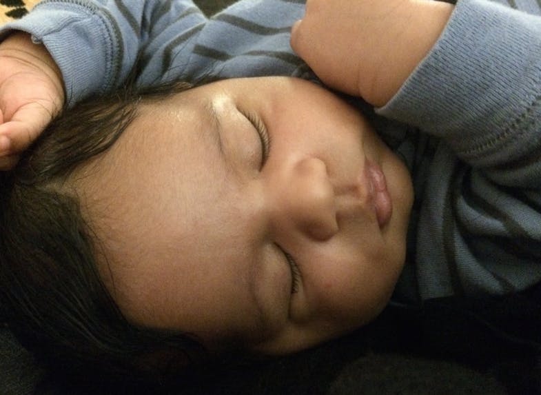 Child sleeping with hands near head