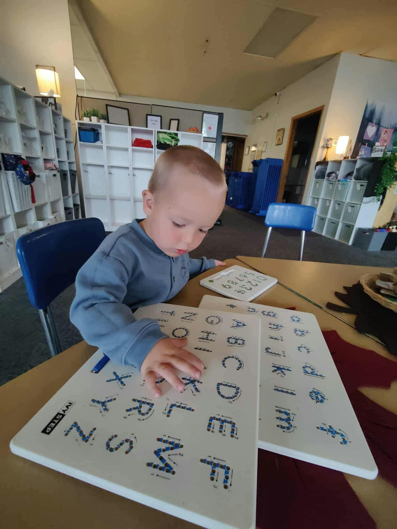 Child tracing letters on an alphabet board in a classroom