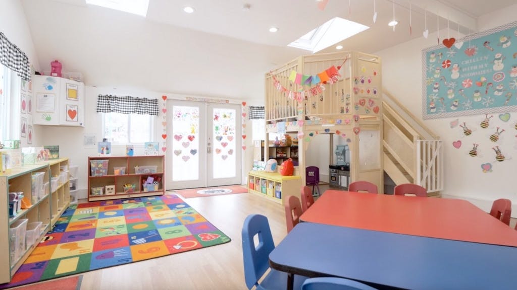 Playroom with colorful rug, tables, and play structure