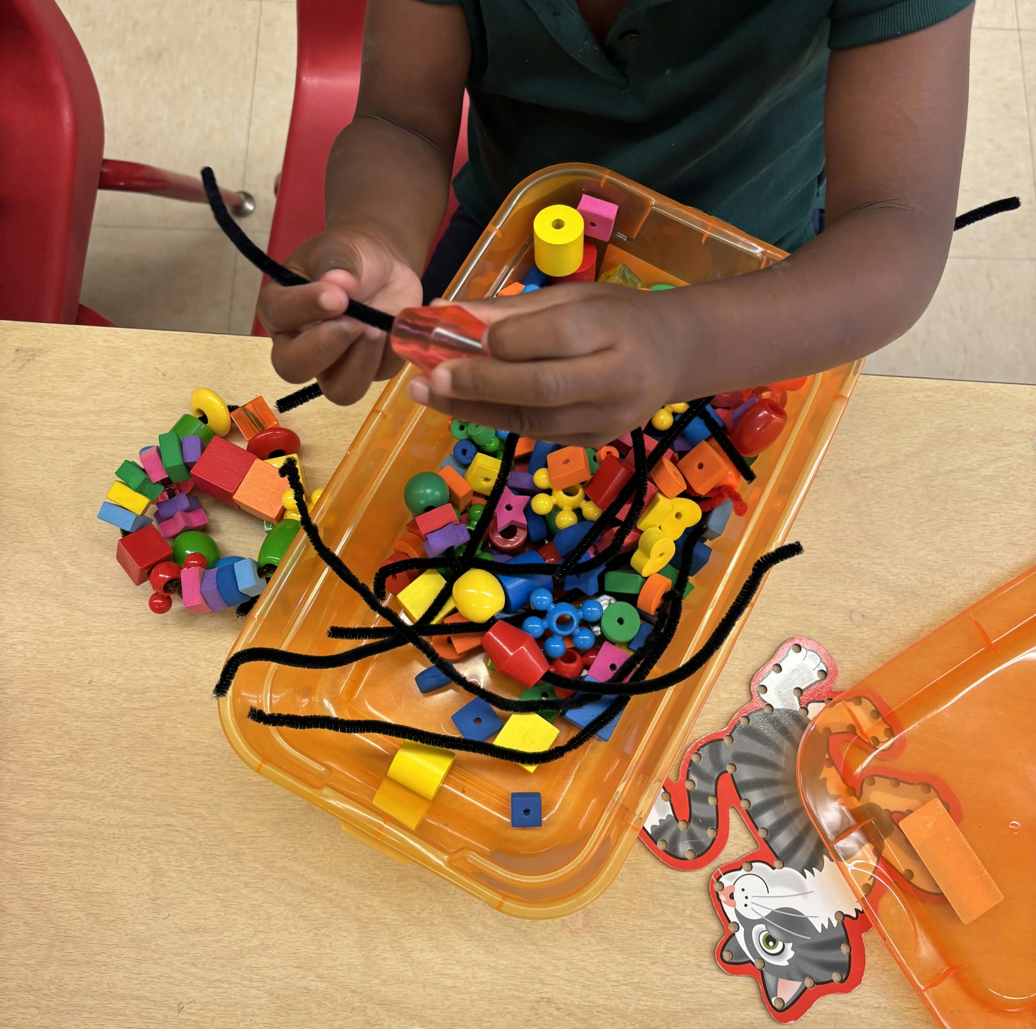 Child threading colorful beads onto a pipe cleaner