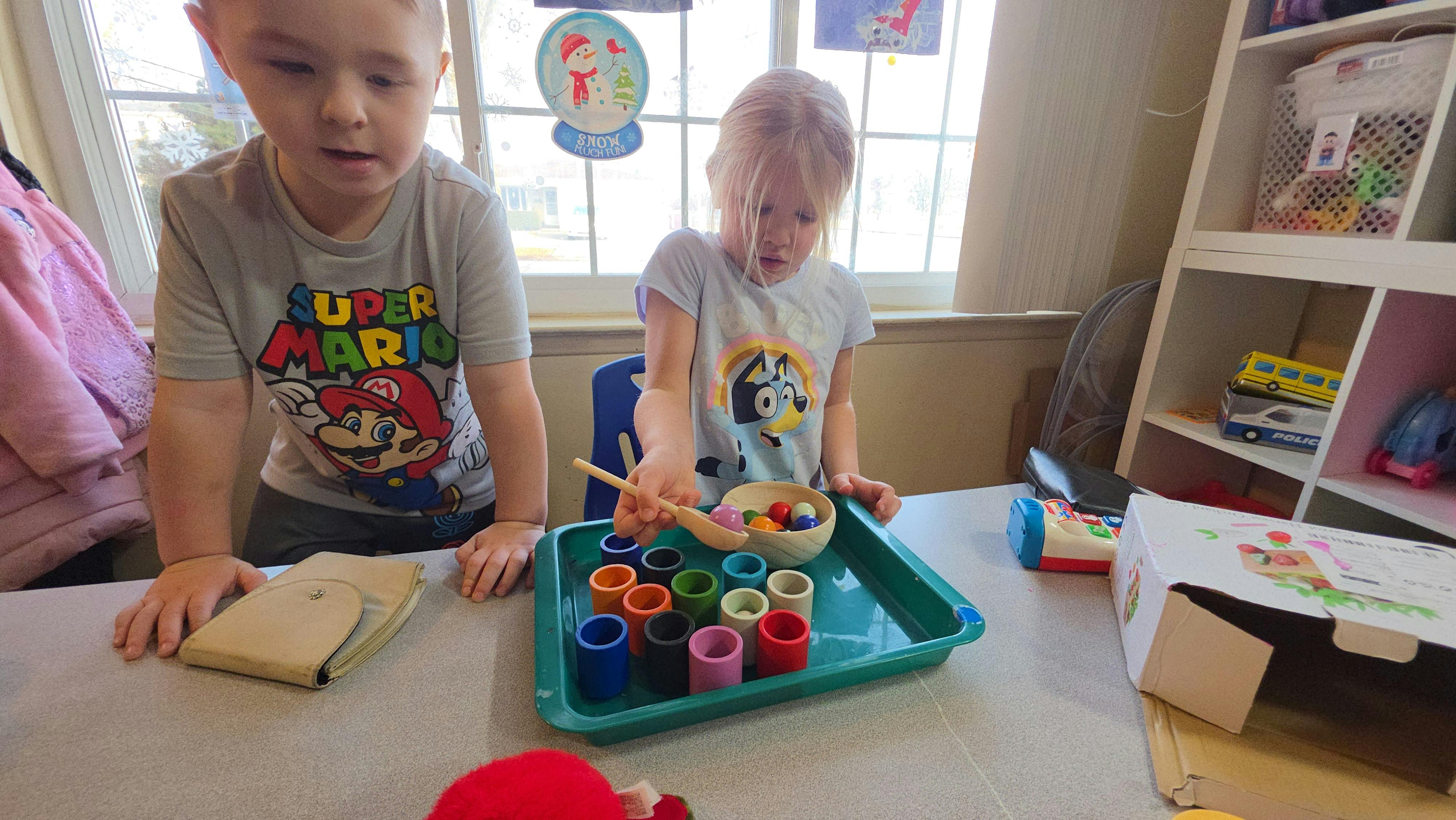 Two children playing with a color sorting game at a table