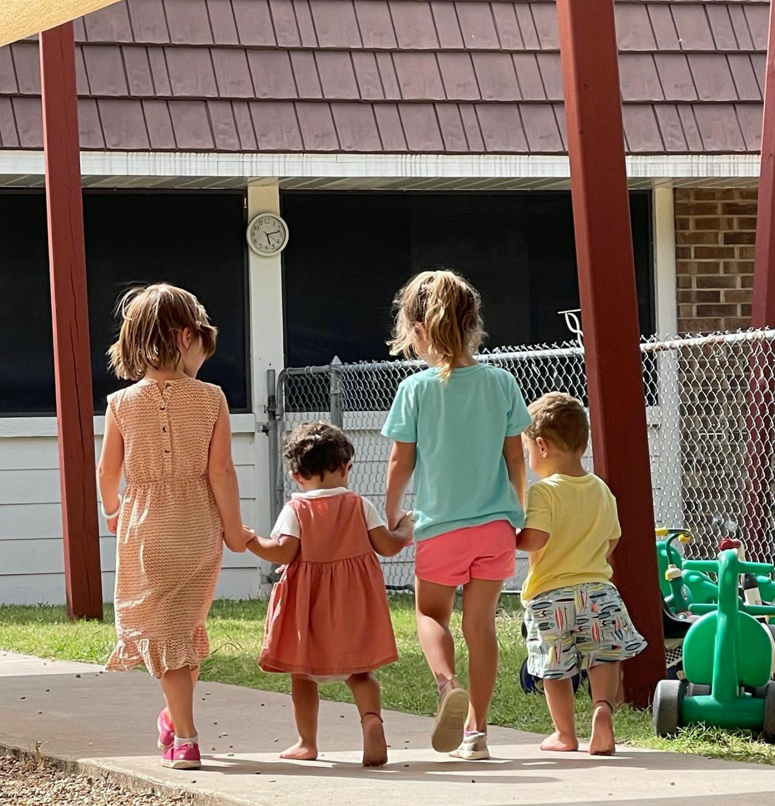 Four children walking away from the camera, holding hands