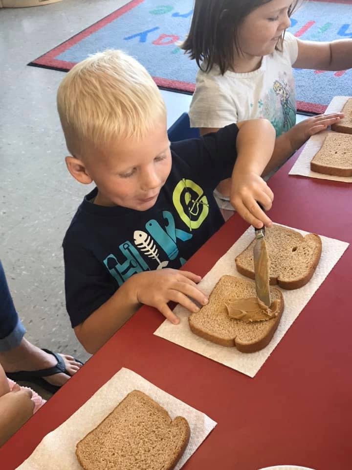 Child spreading peanut butter on bread