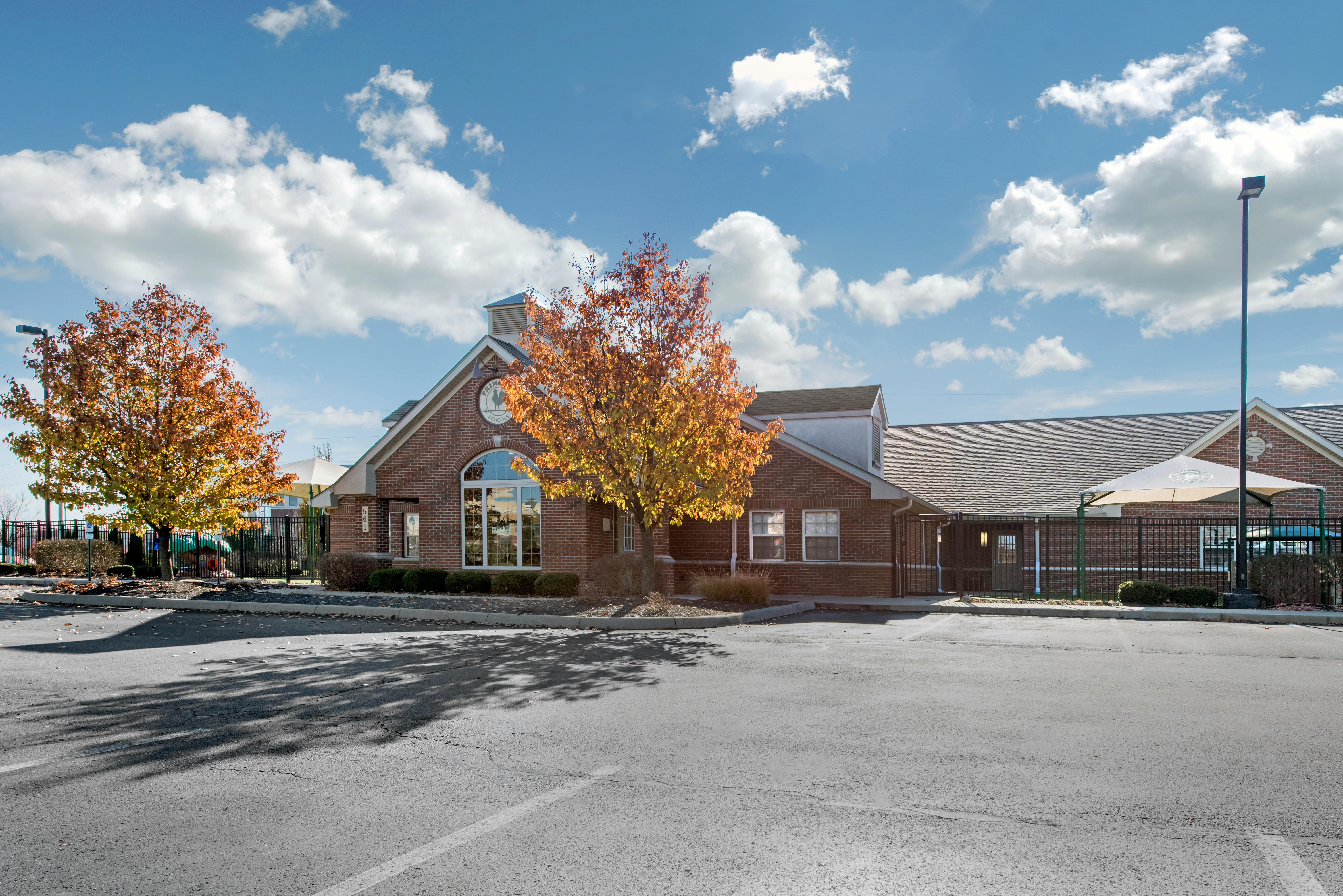 Brick building with a parking lot and autumn trees in front