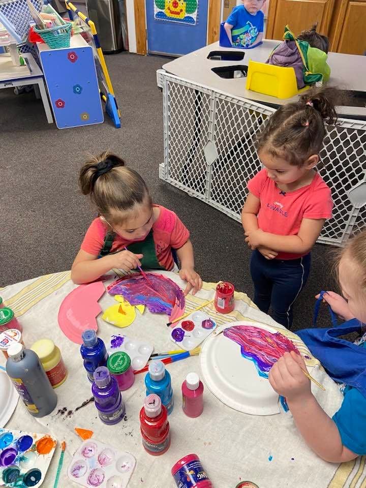 Child painting at a table with other children