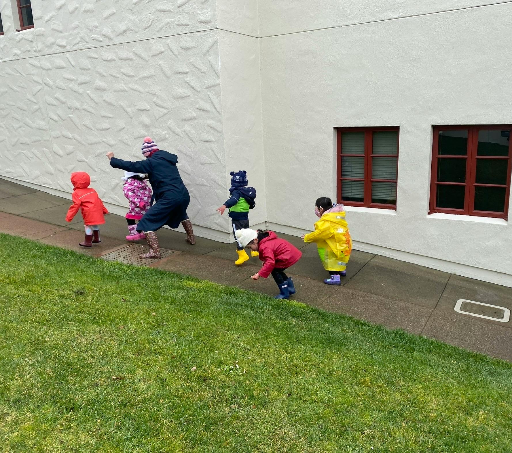 Adult and children playing on a sidewalk next to a building