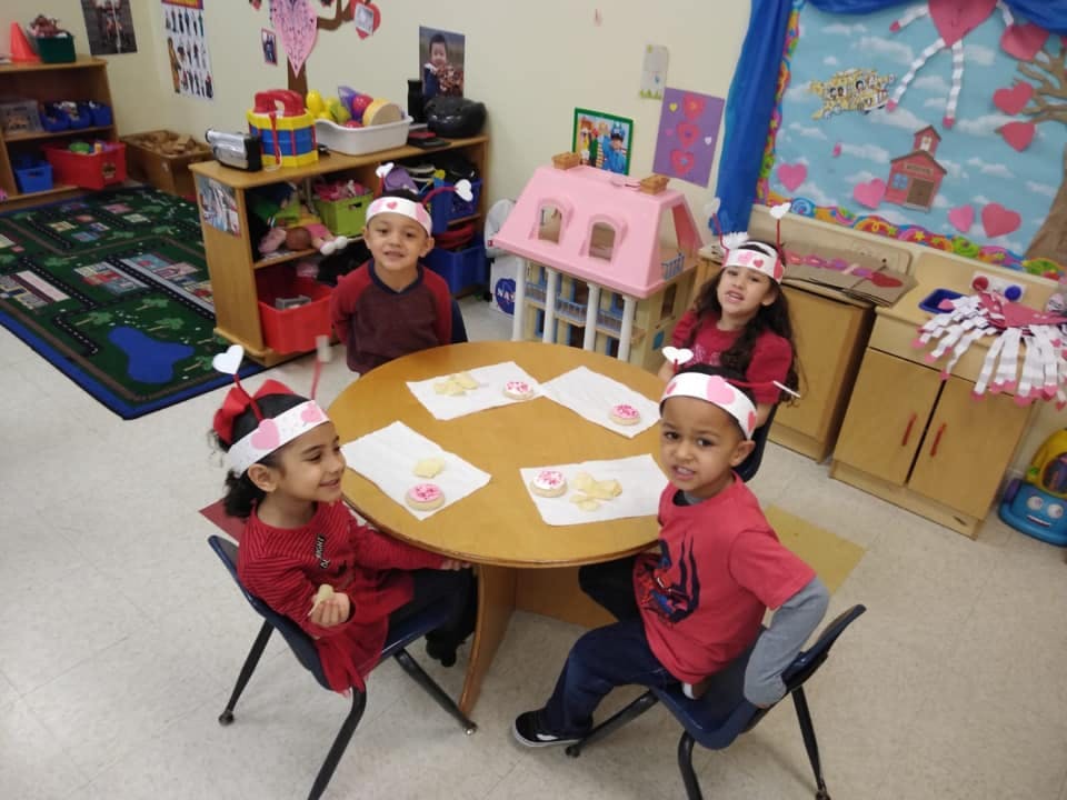 Four children sitting at a round table in a classroom