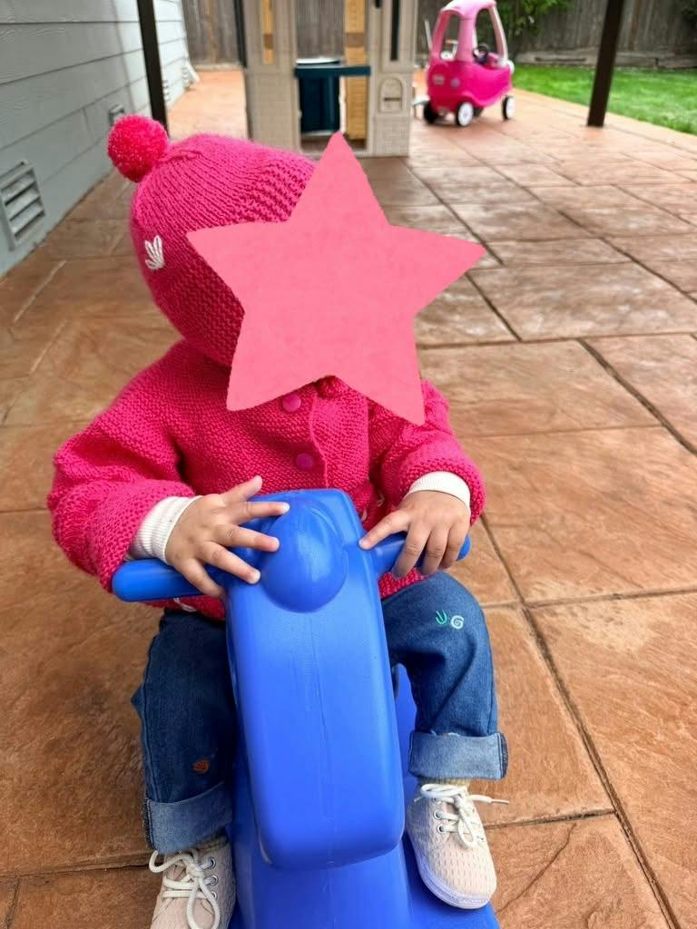 Child riding a blue plastic toy on a patio