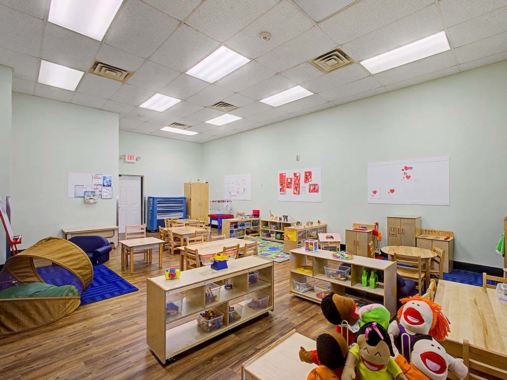 Empty classroom with small tables, chairs, shelving units, and a tent