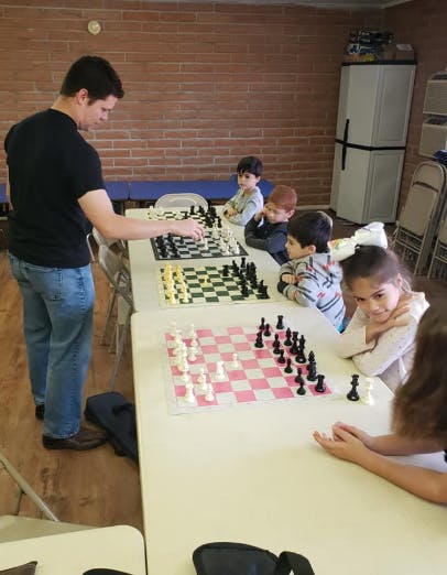 Person teaching children to play chess