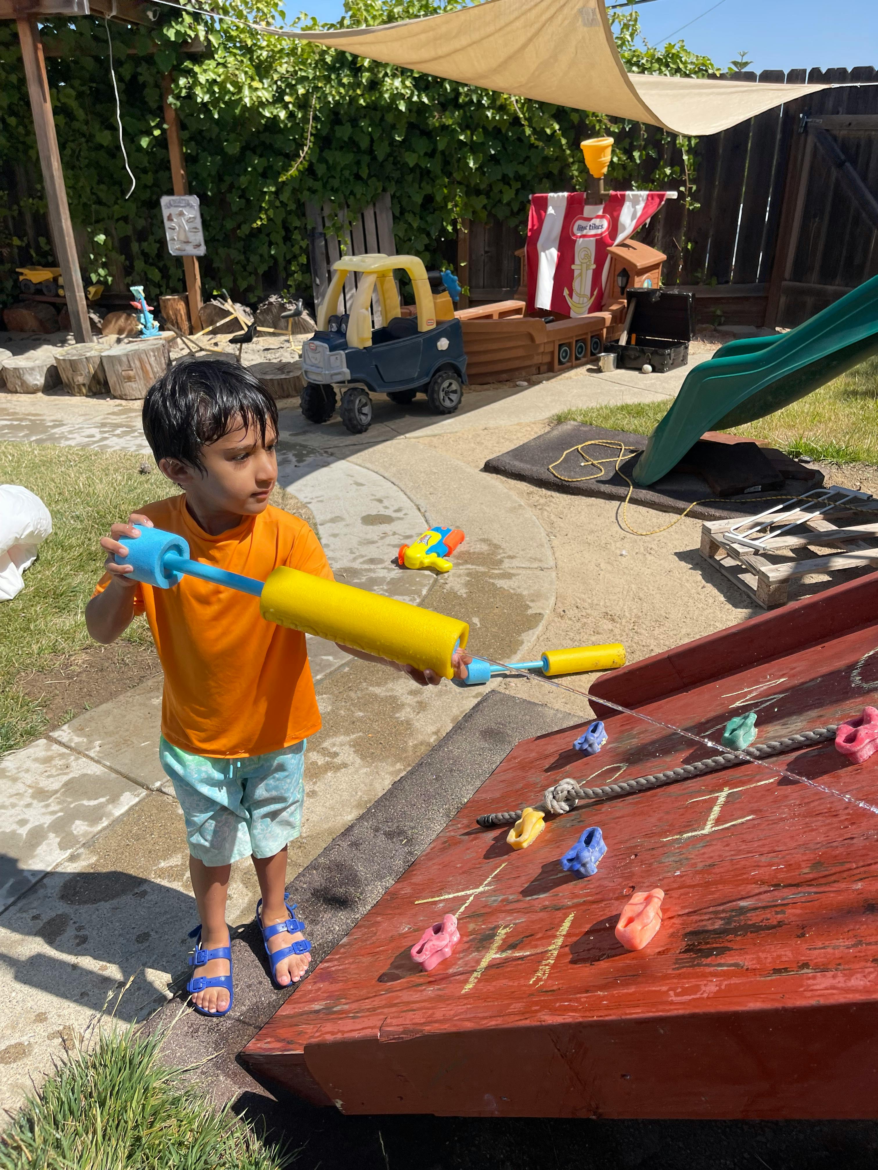 Child holding a water toy in a play area