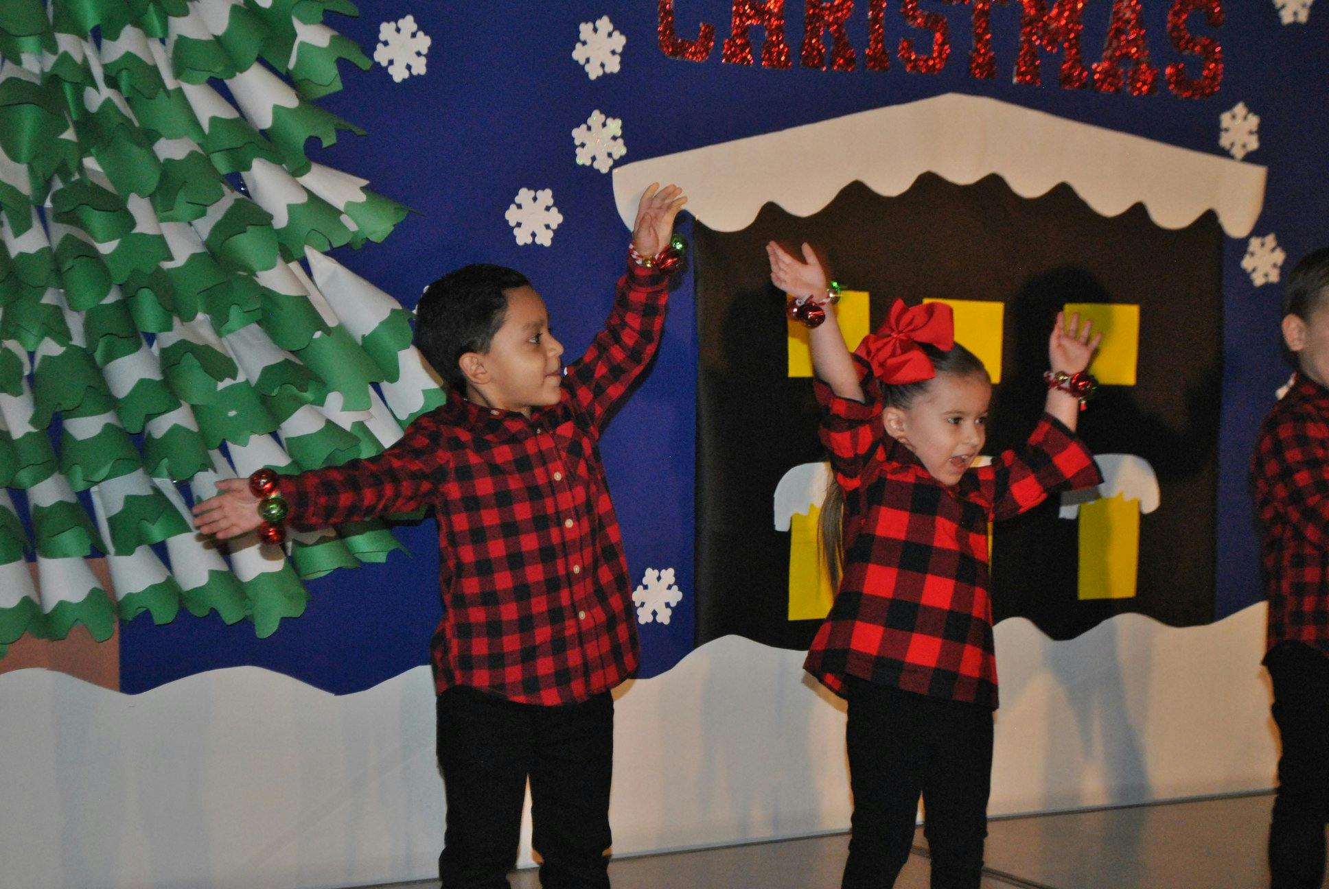 Two children in plaid shirts with arms raised