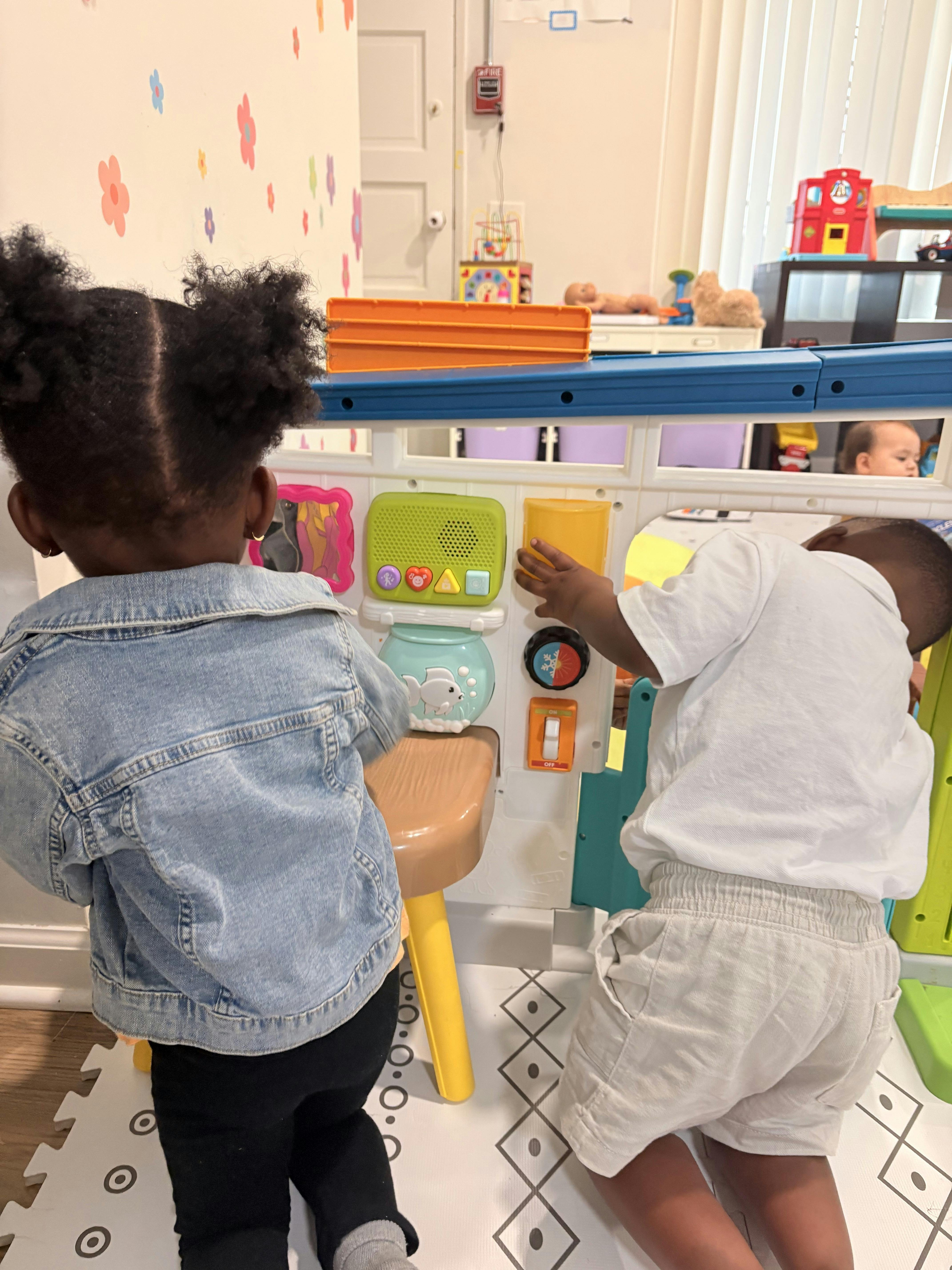 Two children playing with a colorful plastic activity center
