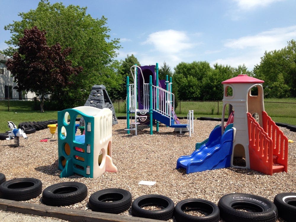 Playground with slides, climbing structures, and tires on a wood chip surface