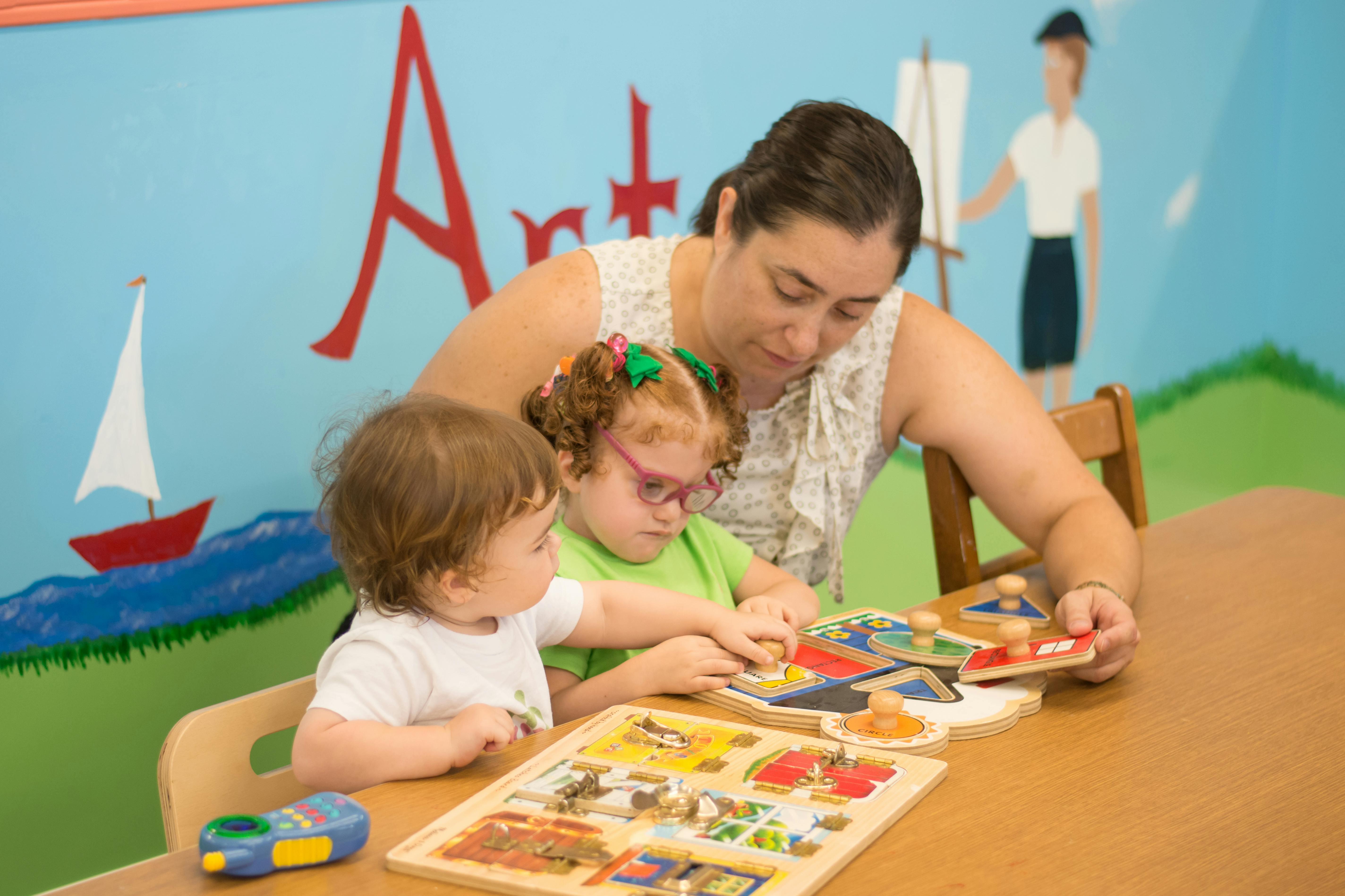 Adult and two children playing with puzzles at a table