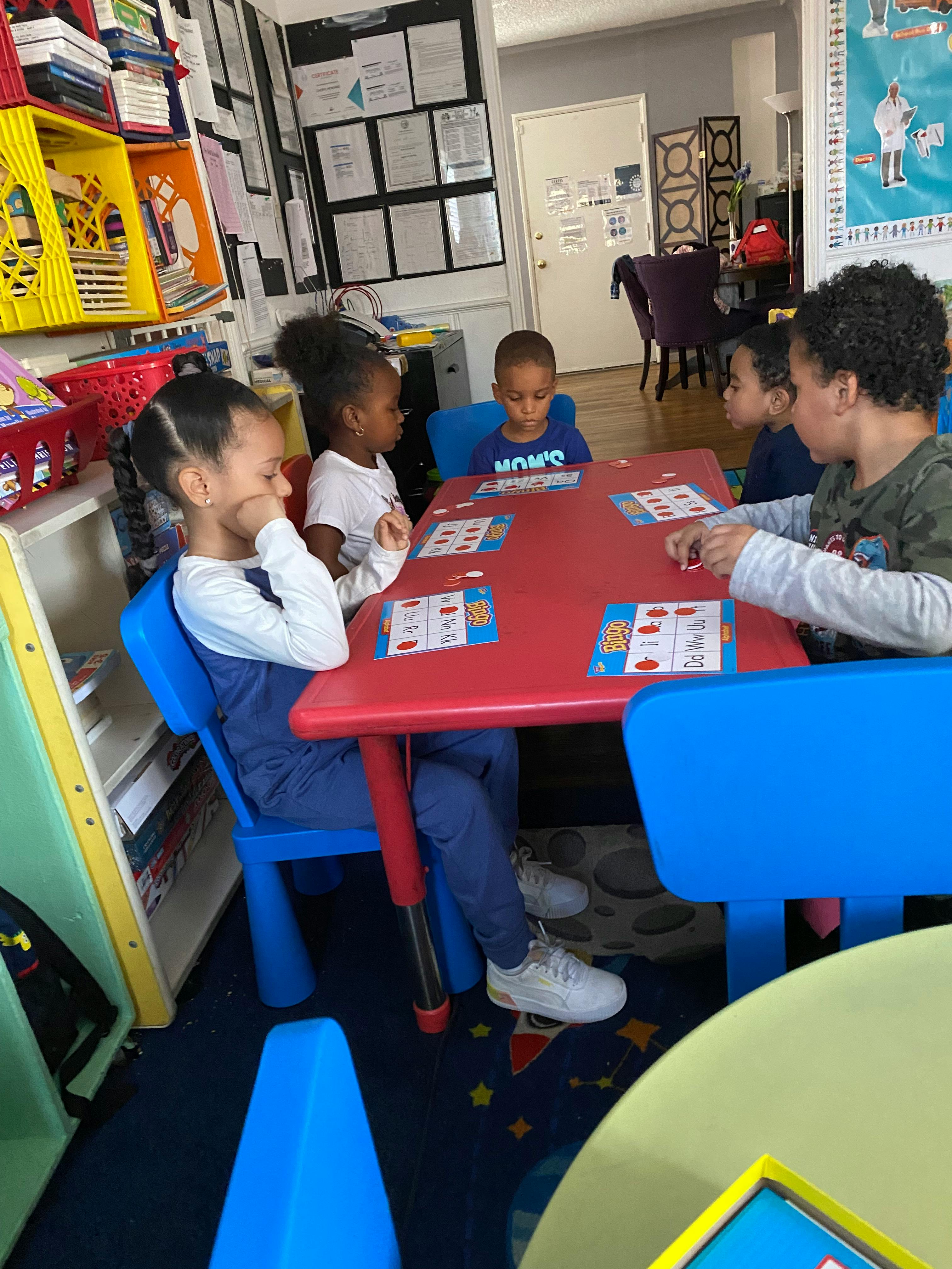 Group of children playing bingo at a table in a classroom