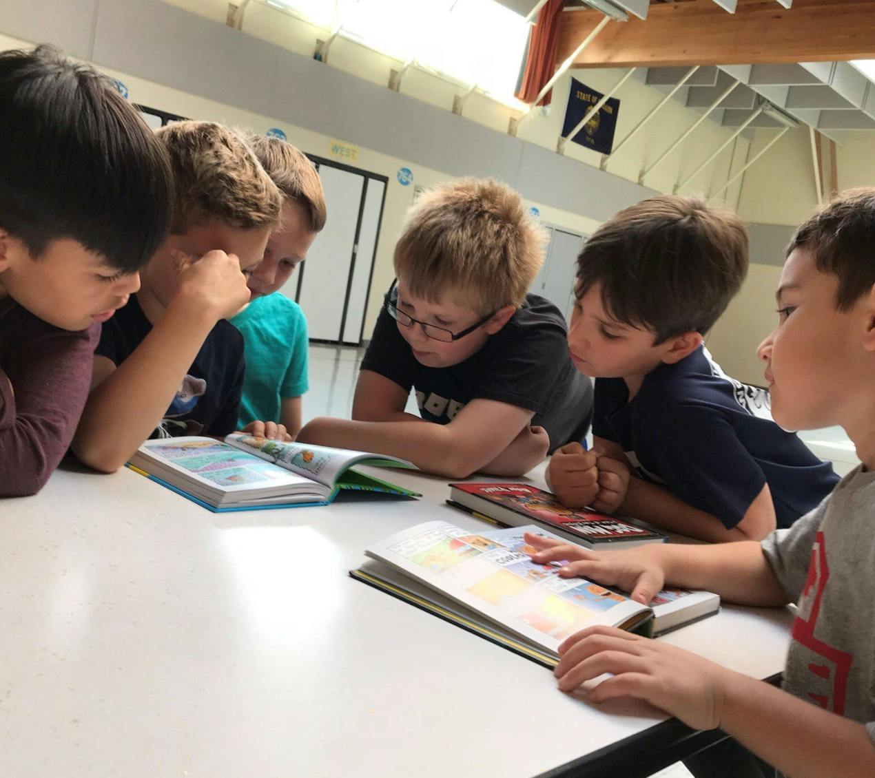 Children reading books together at a table