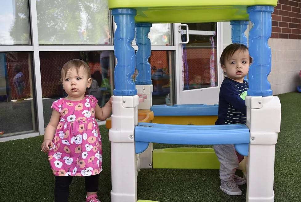 Two children playing on a colorful plastic play structure