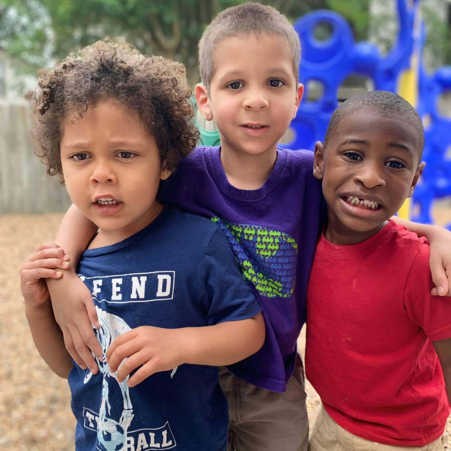 Three children standing together with arms around each other