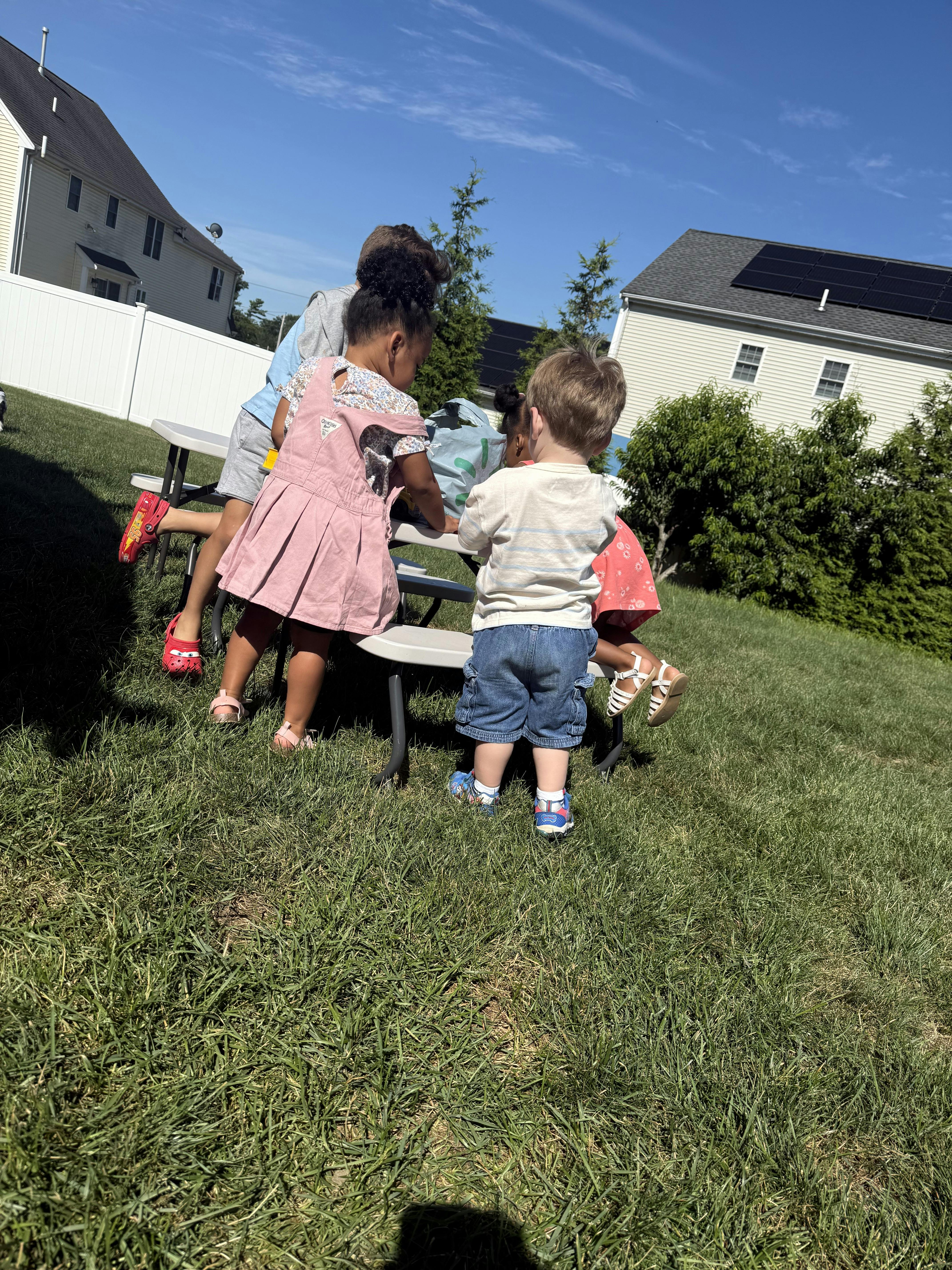 Children gathered around a picnic table outdoors