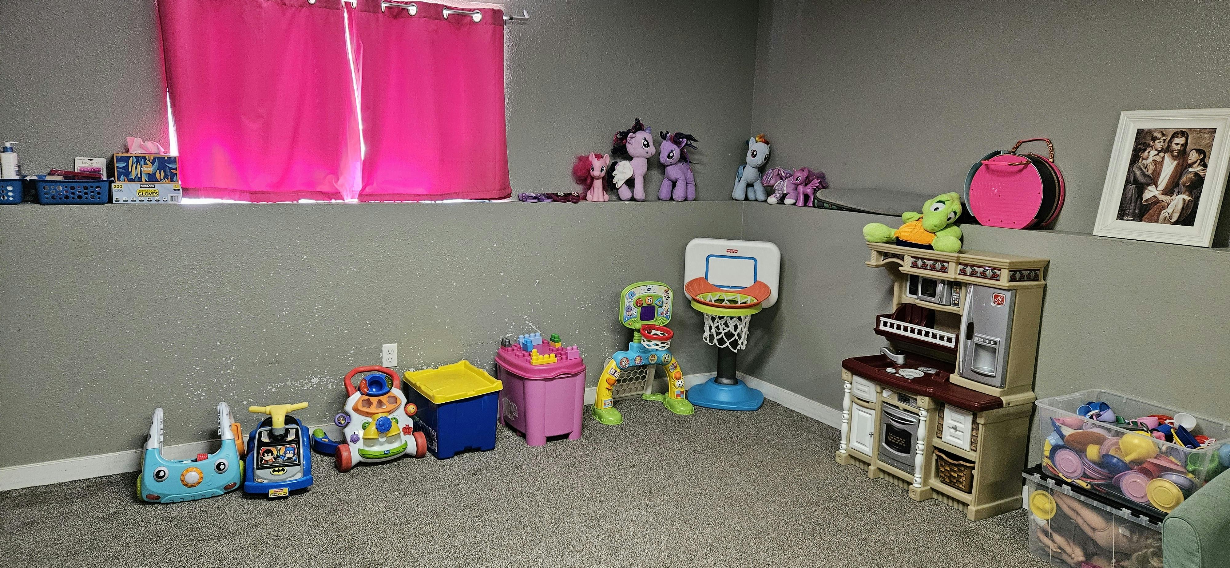 Children's toys in a room with pink curtains