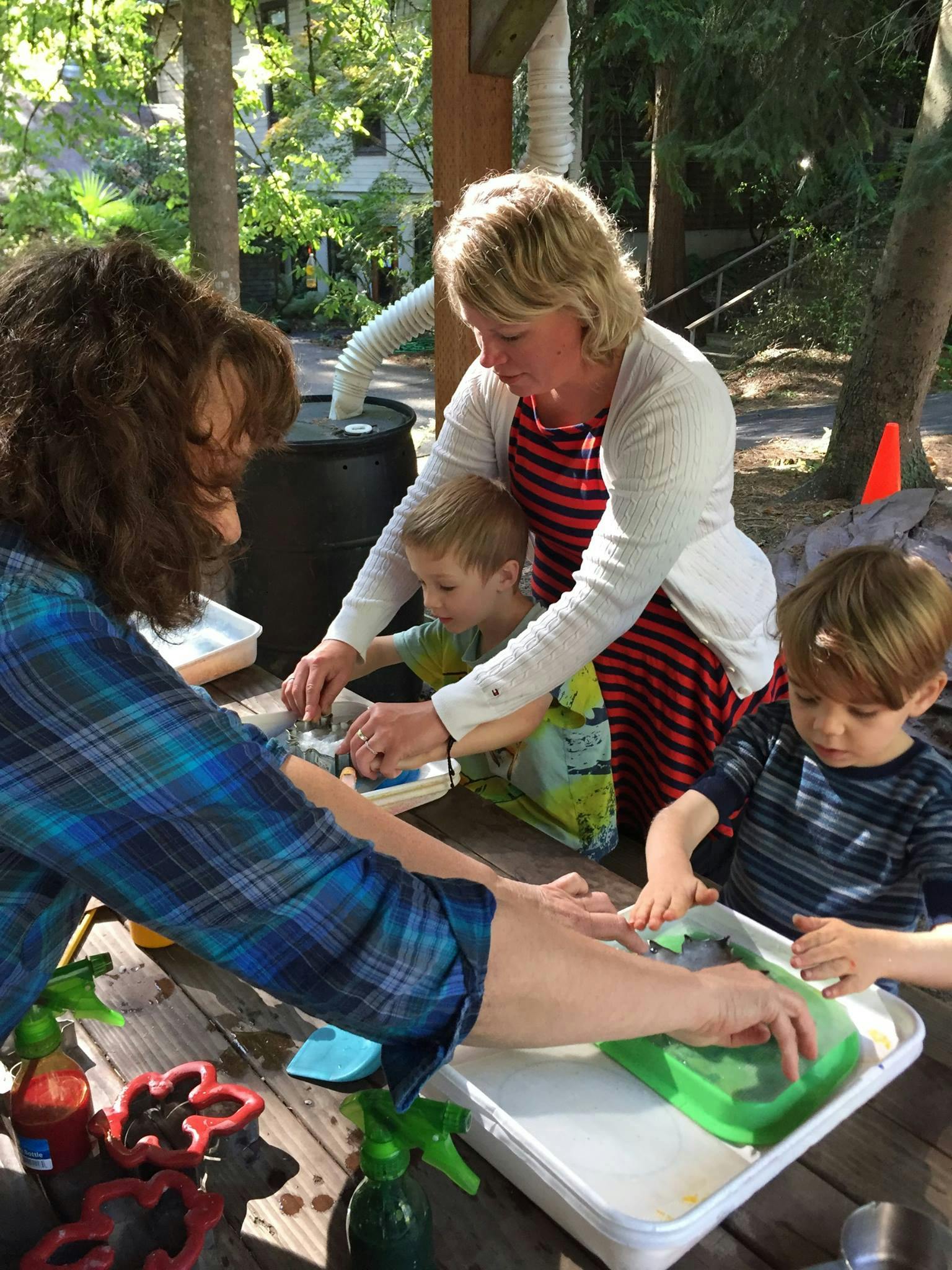 Two adults and two children engaged in an activity at a table outdoors