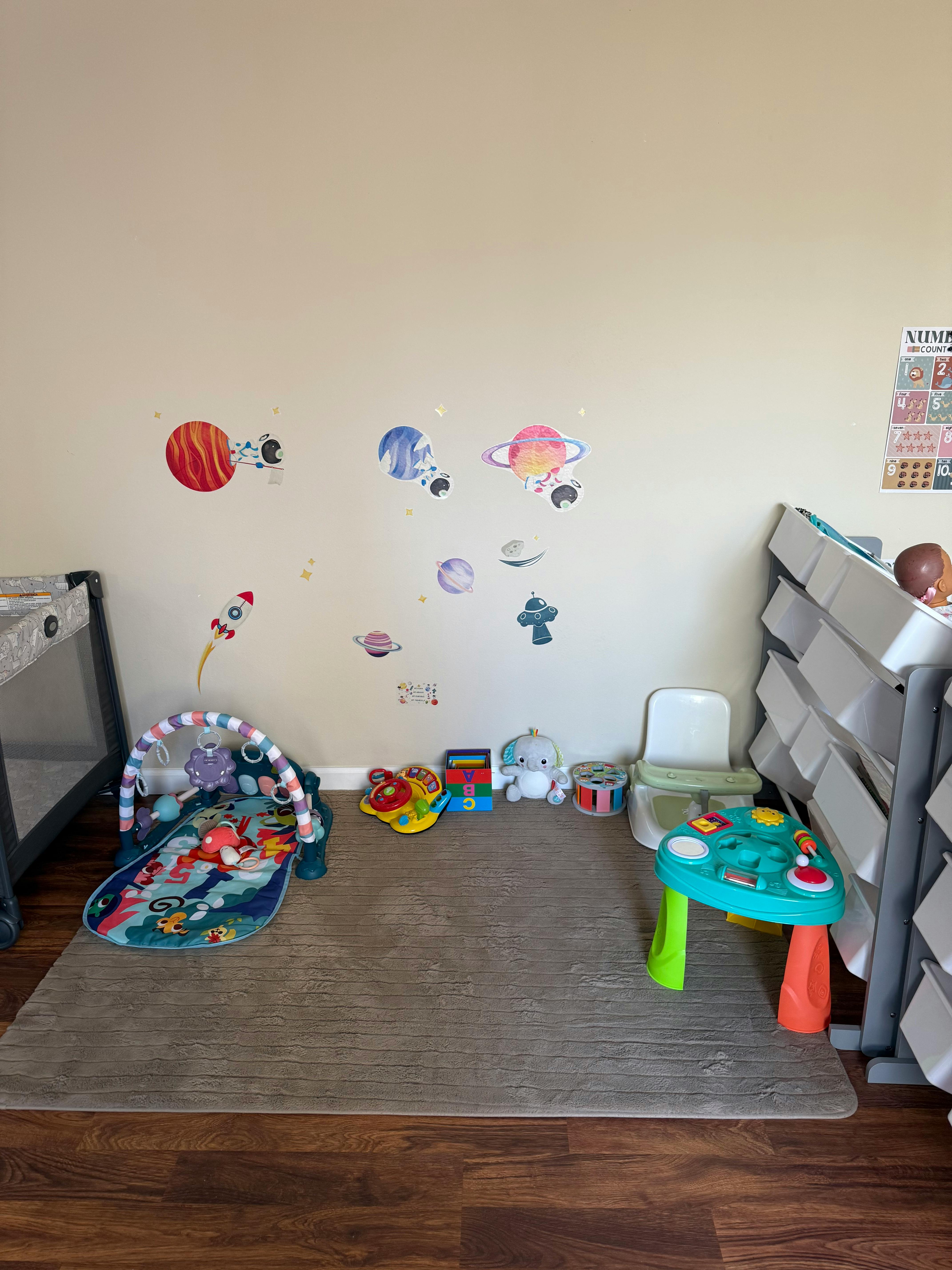 Nursery room with space-themed wall decals, play mat, and toys