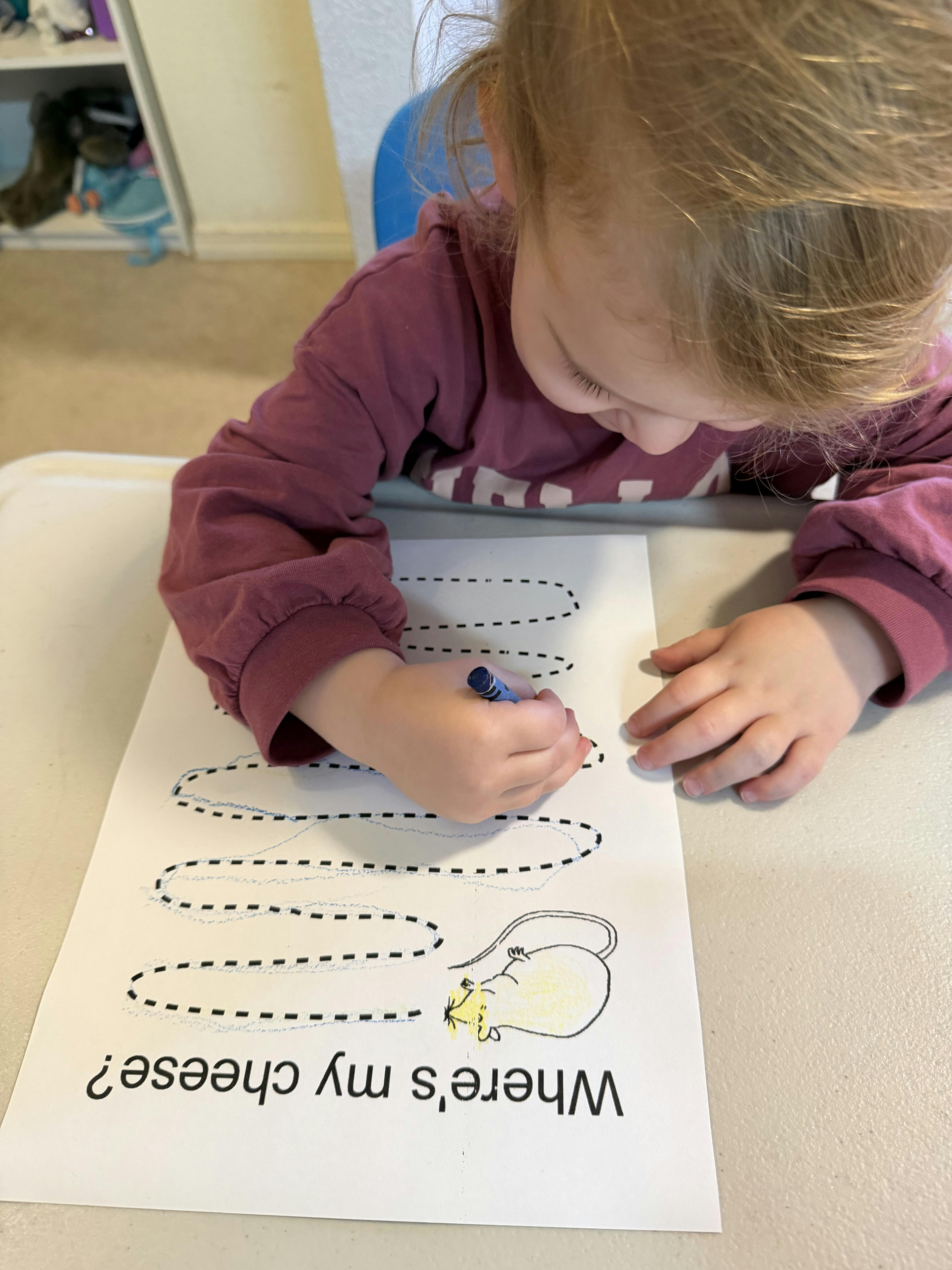 Child tracing dotted lines on a paper with a crayon