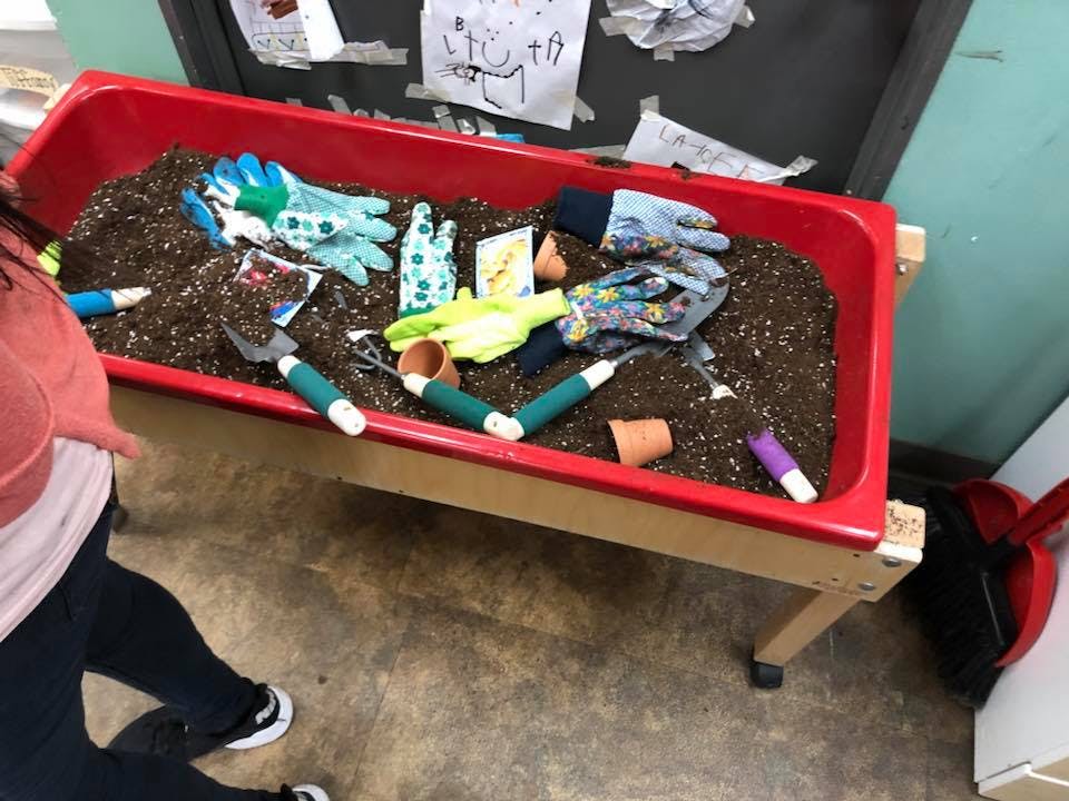 Red bin with soil, gardening gloves, and small tools