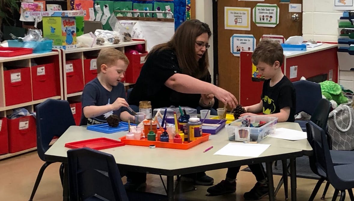 Adult and two children at a table with craft supplies