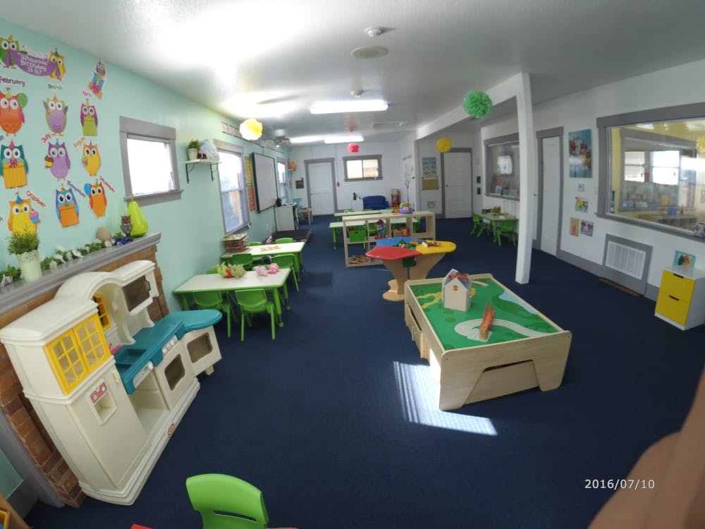 Playroom with small tables and chairs, play kitchen, and activity table