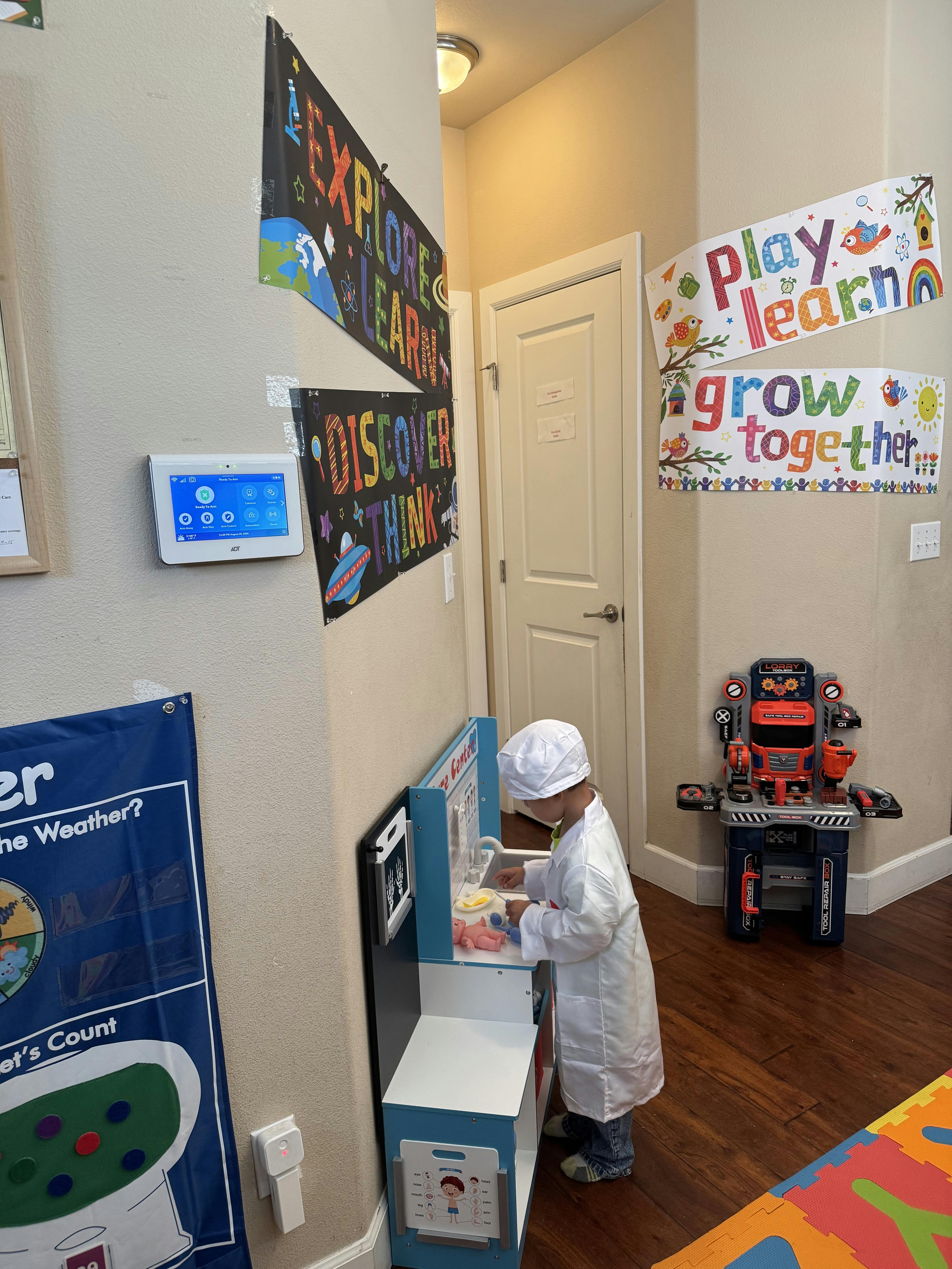 Child wearing a lab coat and hat playing with a toy medical station