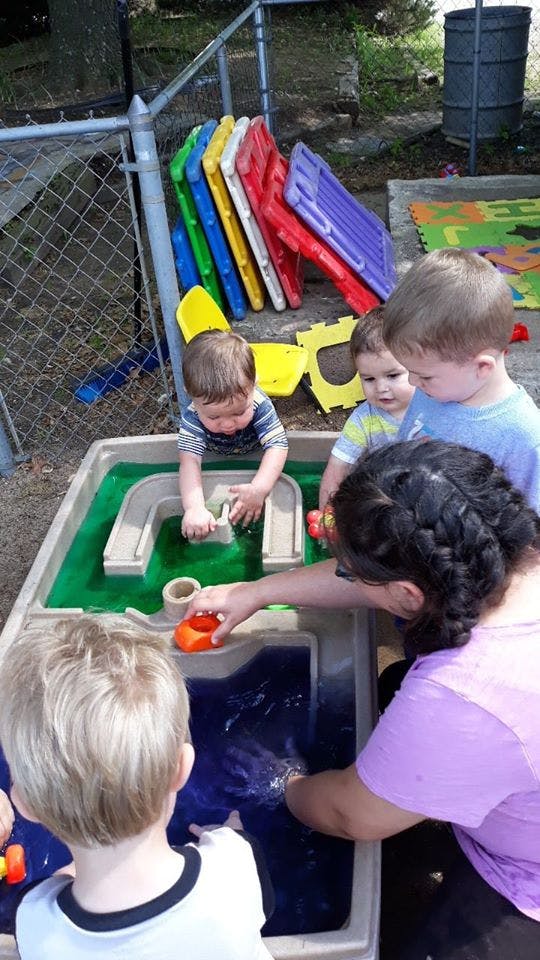 Adult and children playing with a water table outdoors