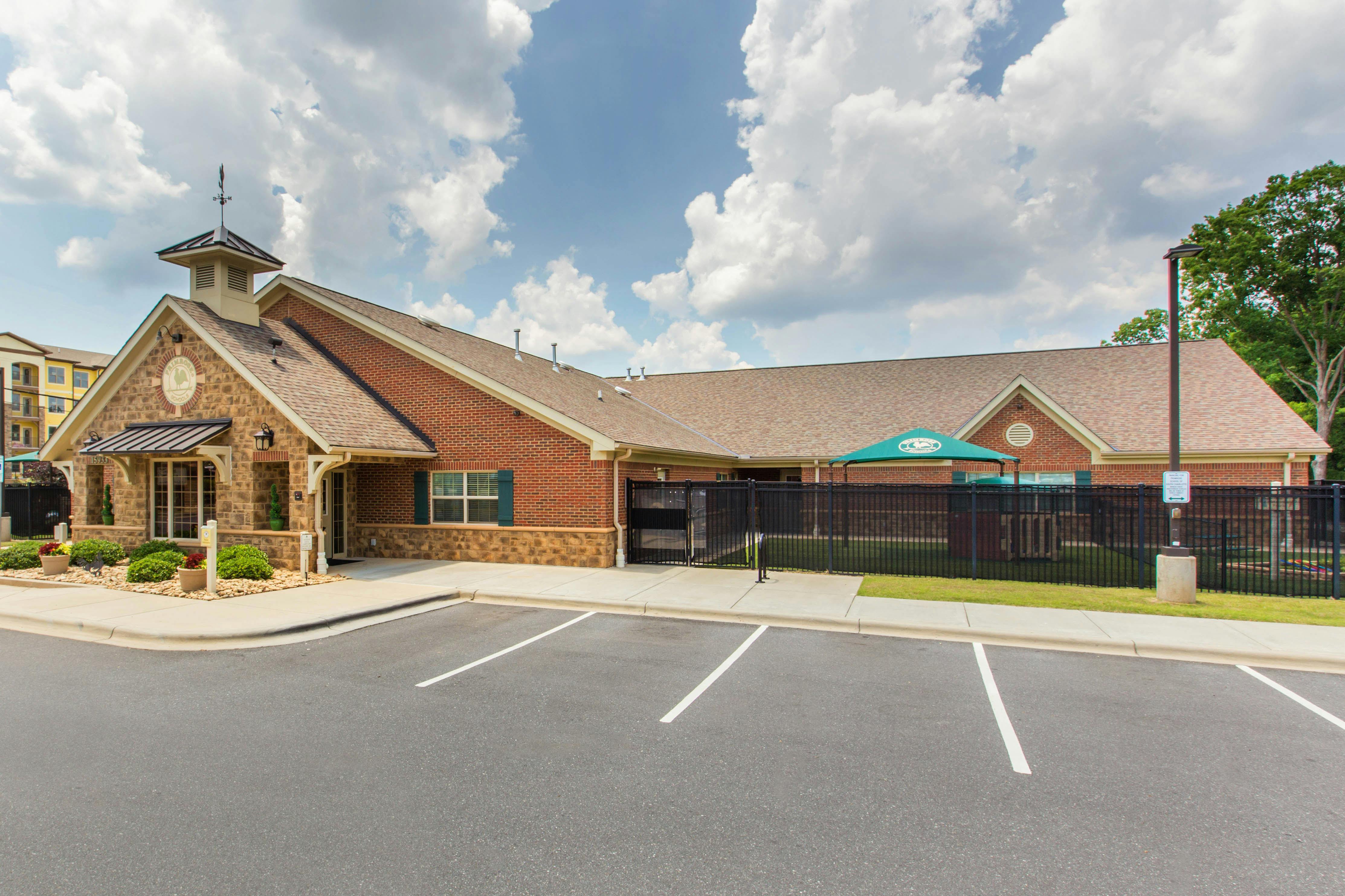 An exterior view of a building with brick and stone, an asphalt parking lot in the foreground