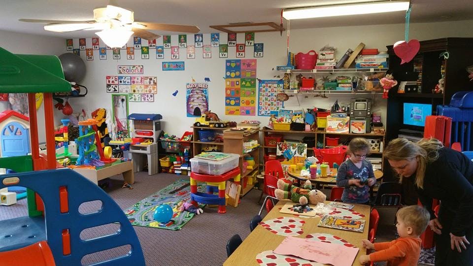 Adult and two children in a classroom with toys and art supplies