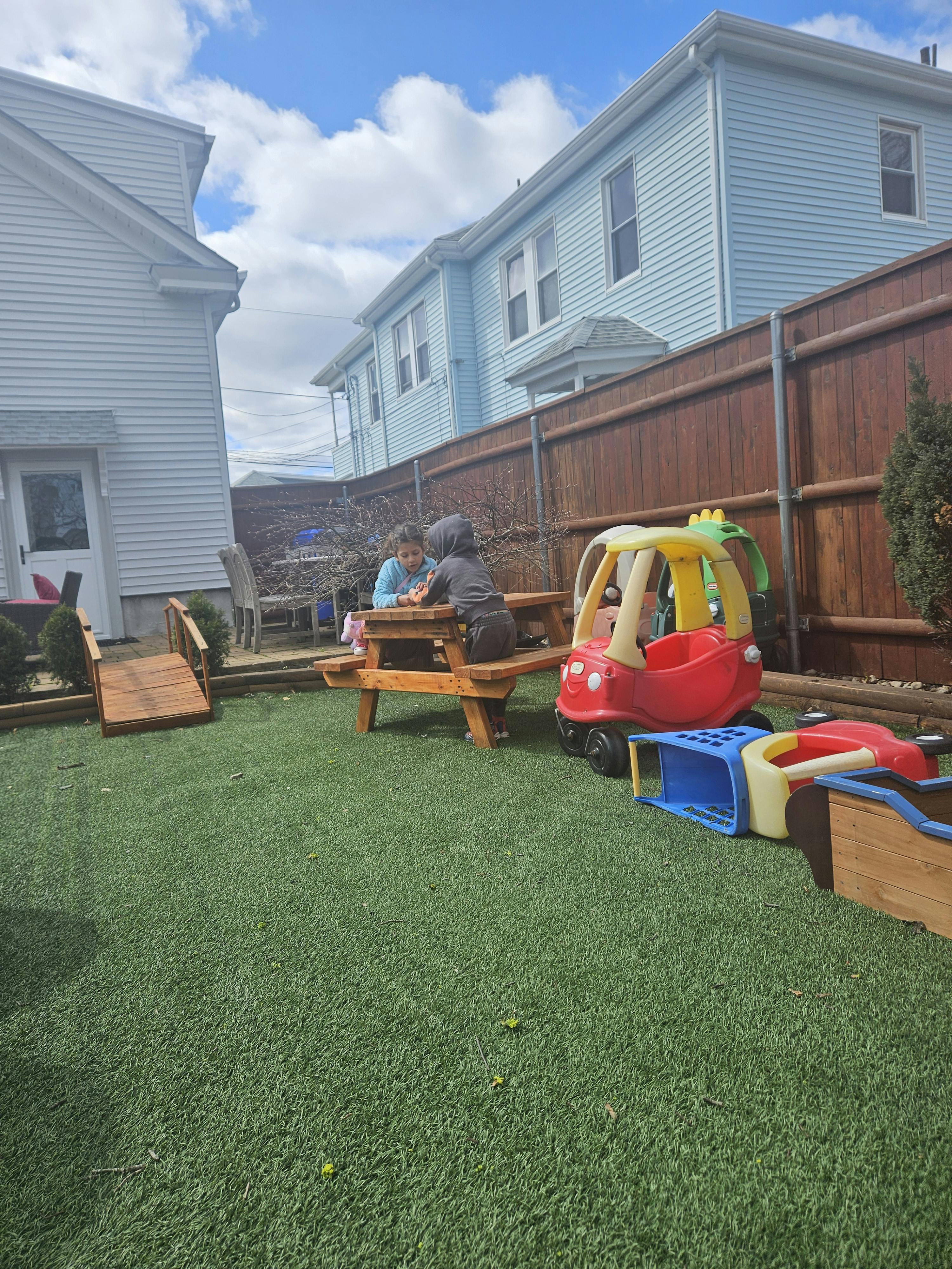 Two people sitting at a picnic table in a grassy backyard