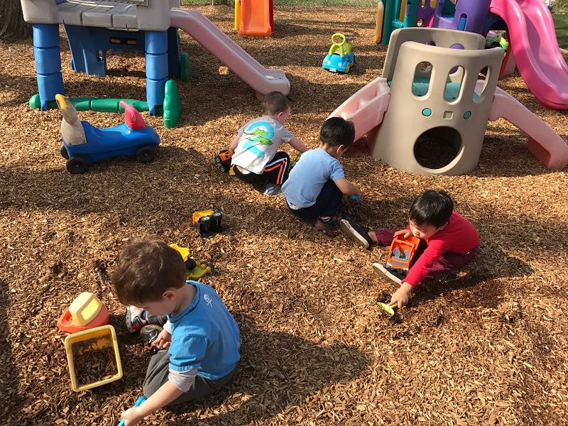 Children playing with toys on wood chips in a playground