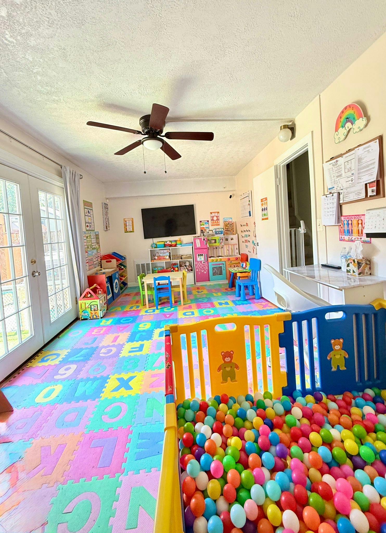 Playroom with colorful alphabet floor mats and a ball pit