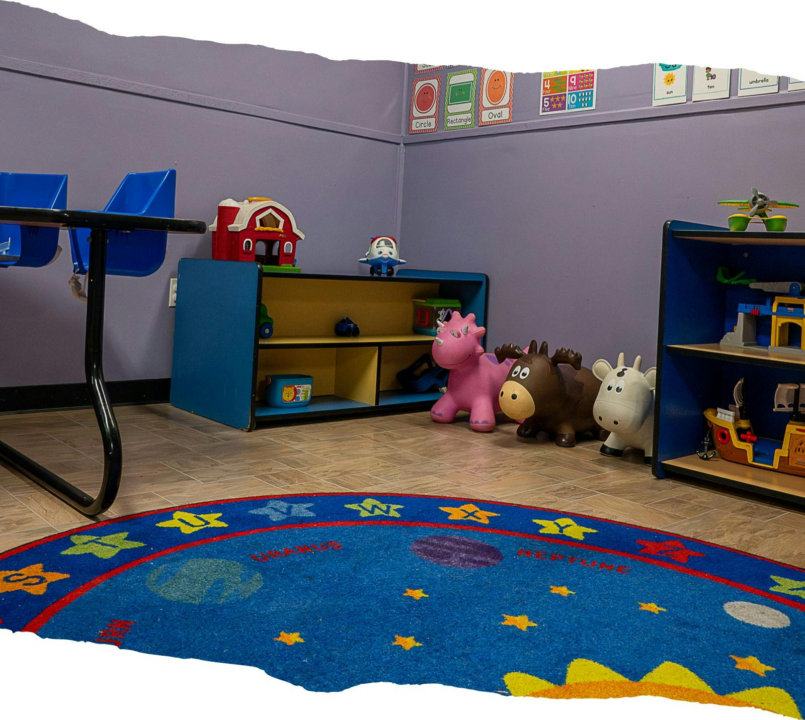 Playroom with blue rug, shelves of toys, and animal hoppers