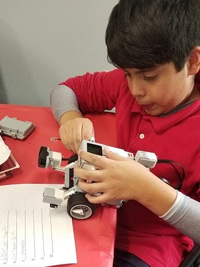 Child assembling a robot on a red table