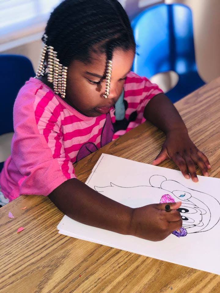 Child coloring a drawing at a table