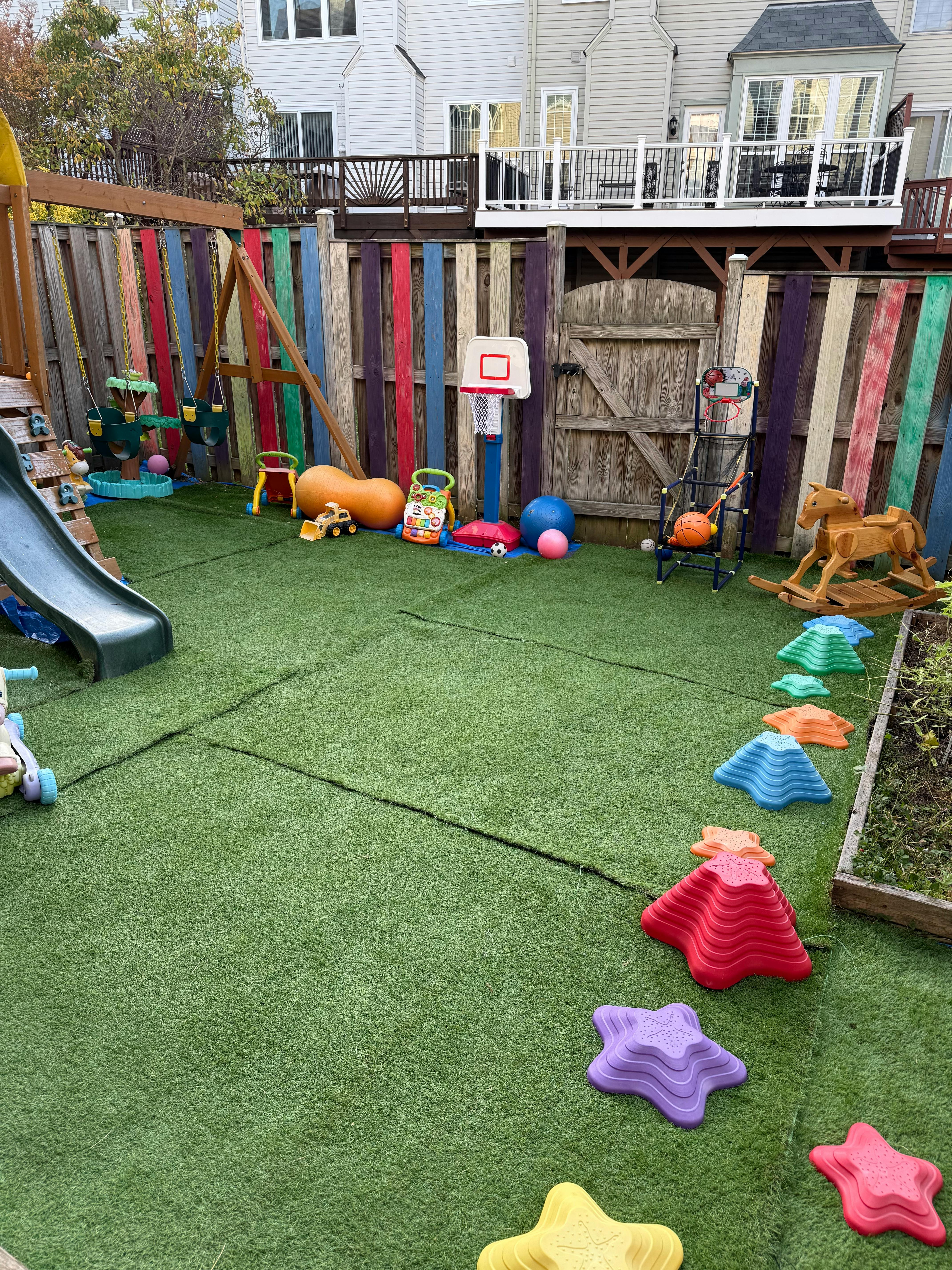 Backyard playground with slide, swings, basketball hoop, and colorful stepping stones